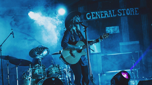 A lady singer singing and playing a guitar performing on a stage