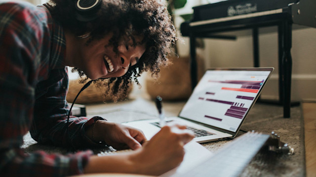 Woman with headphones on writing a song