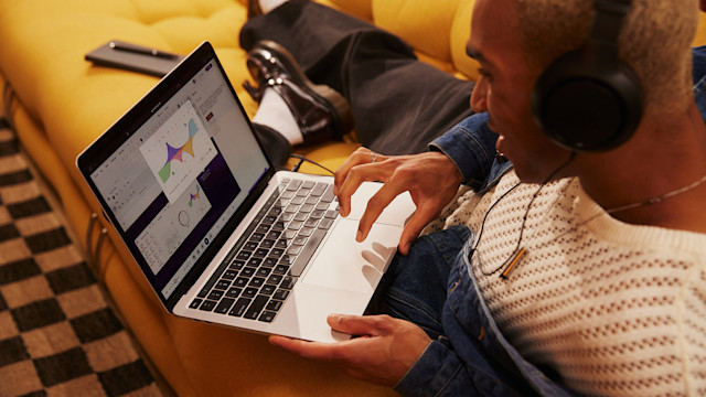 Man on couch mixing music on his laptop