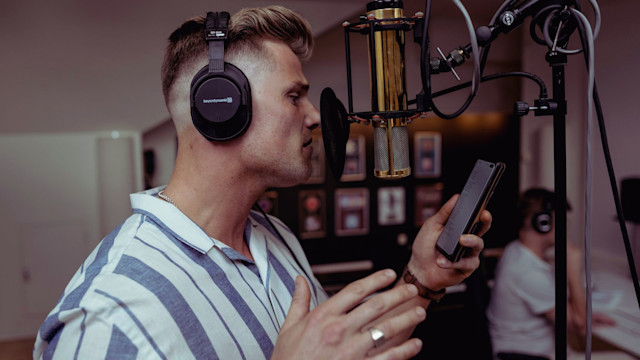 Man recording vocals over a mic in a studio