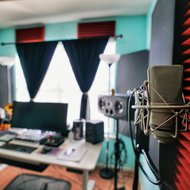 Square image of a home studio with a mic in the foreground