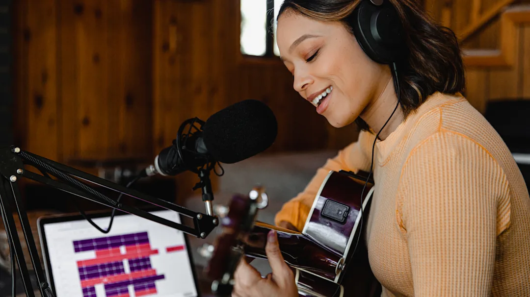 Women playing guitar and singing into a microphone using Auto-Tune