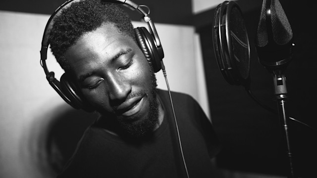 Male singer recording vocals over a mic in the studio