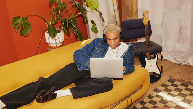Man on couch making music on his laptop