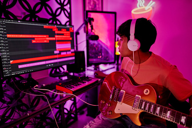 Musician in home studio recording guitar